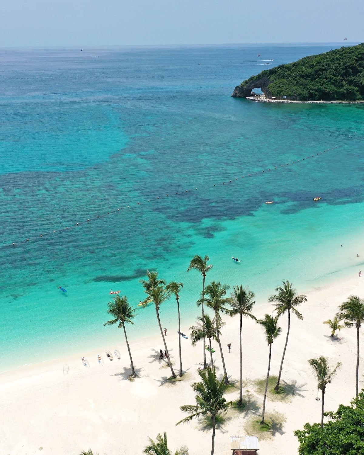 Turquoise water, white sand and palms at Boracay Newcoast, with the Keyhole headland
